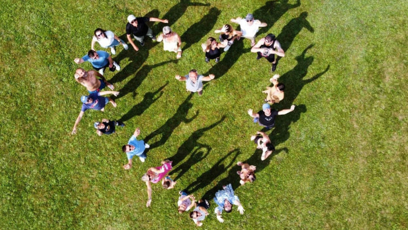 groupe de personnes qui forment un coeur, debout dans l'herbe